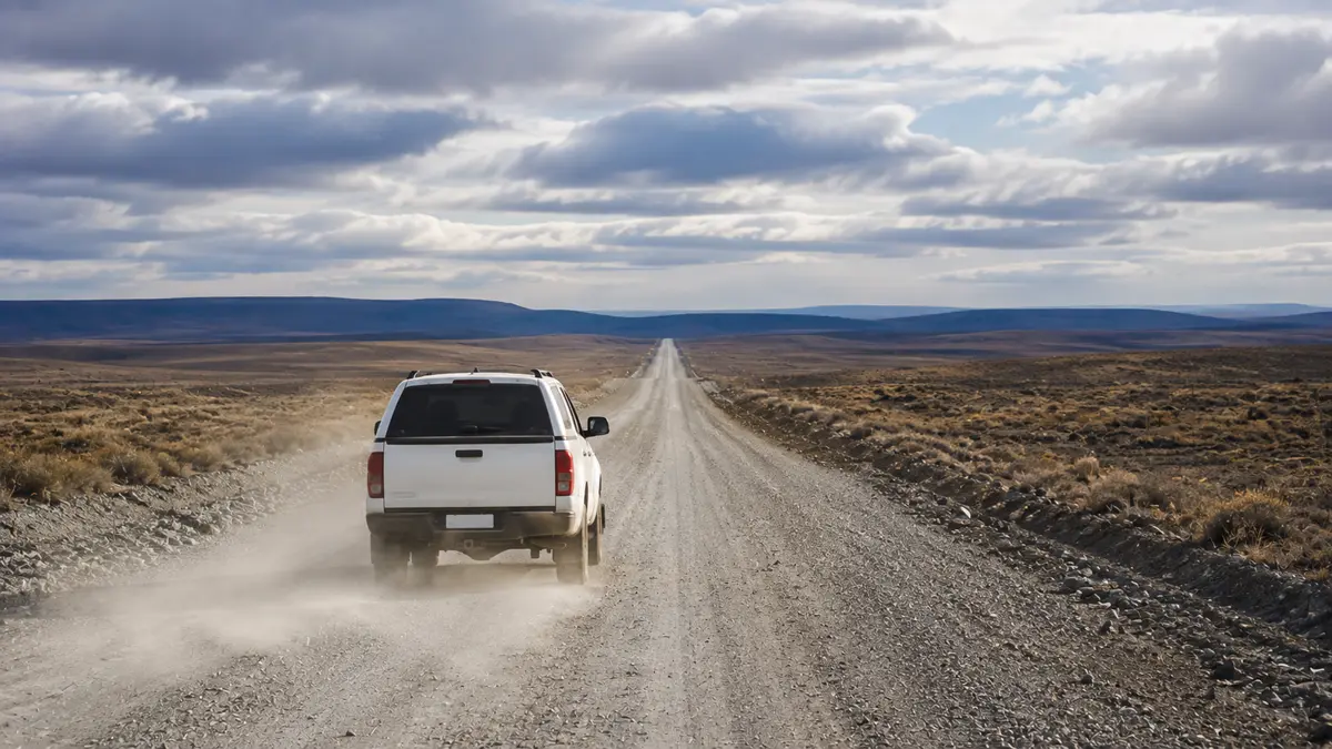 Camioneta circulando por una ruta de ripio en la estepa patagónica